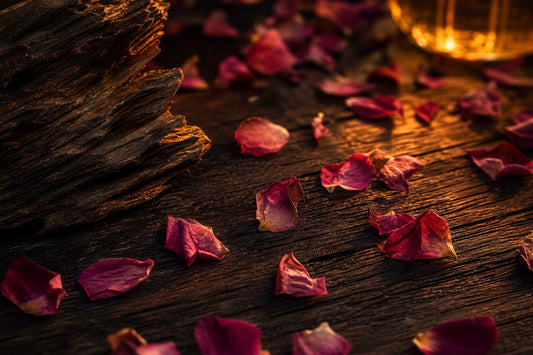 A dark wooden surface with rose petals and an amber glow.