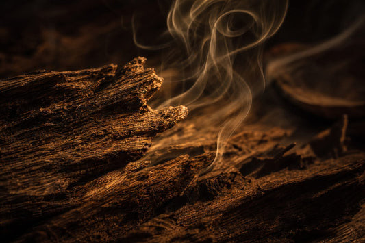 Textured wood background with warm amber tones and curling smoke, creating a warm and mysterious atmosphere.
