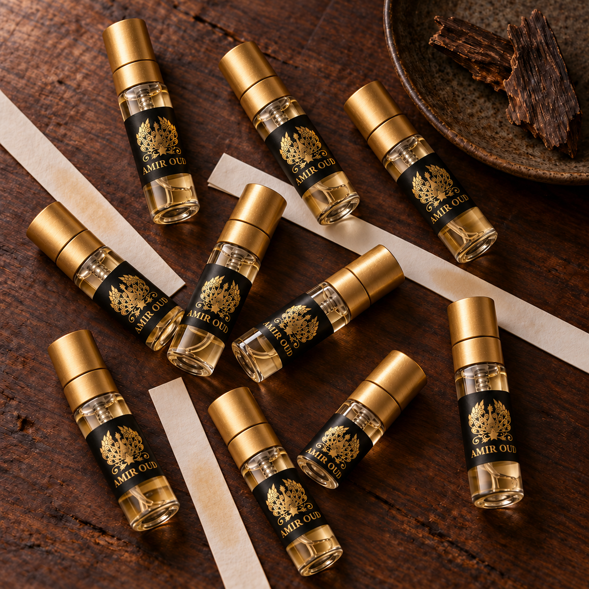 Ten filled Amir Oud 3 ml spray samples arranged with scent strips, product-only discovery still life